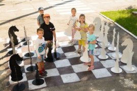 дети в садике на улице играют в шахматы